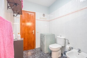 Une salle de bain avec une porte en bois, des toilettes, un bidet, un lavabo et un porte-serviettes.