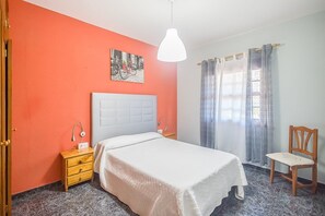 Une chambre à coucher avec un lit, une table de chevet, une chaise et un tableau au mur.