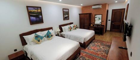 A hotel room with two beds, a desk, a chair, a TV, and a patterned rug.