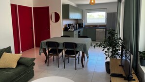 Een ruimtelijk ingerichte leefruimte met een eethoek, kitchenette en een raam met uitzicht.