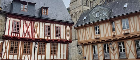 A cobblestone street with traditional half-timbered buildings, a church tower, and a bench.