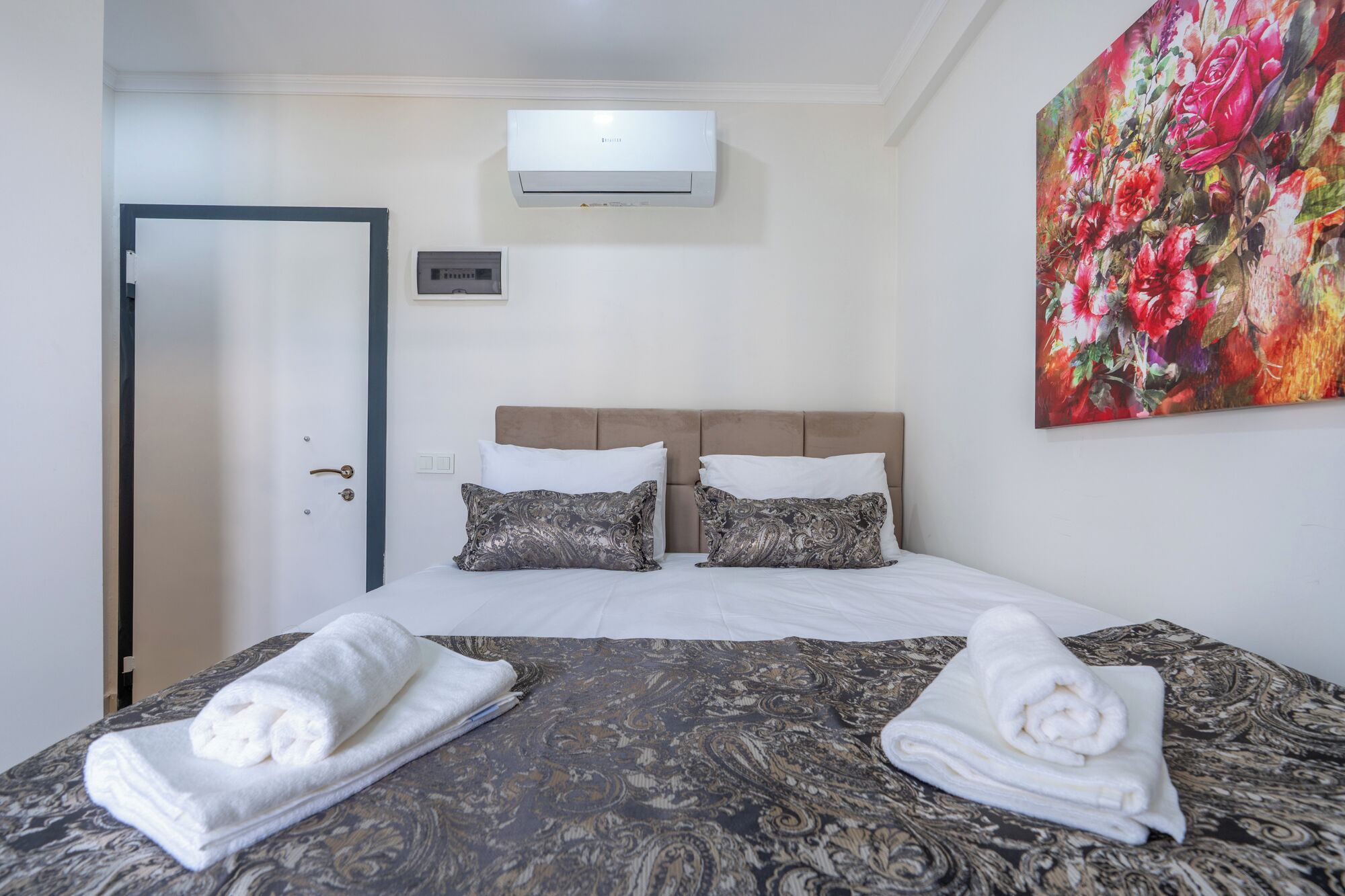 Hotelkamer met een bed, twee kussens, een wandairconditioner en een schilderij.