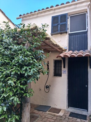 A building with a black door, a small window with shutters, and a water spigot on the wall. - Air-conditioned, secure Laujo house with swimming pool, seafront, Port de Taverna (Santa-Maria-Poggio)