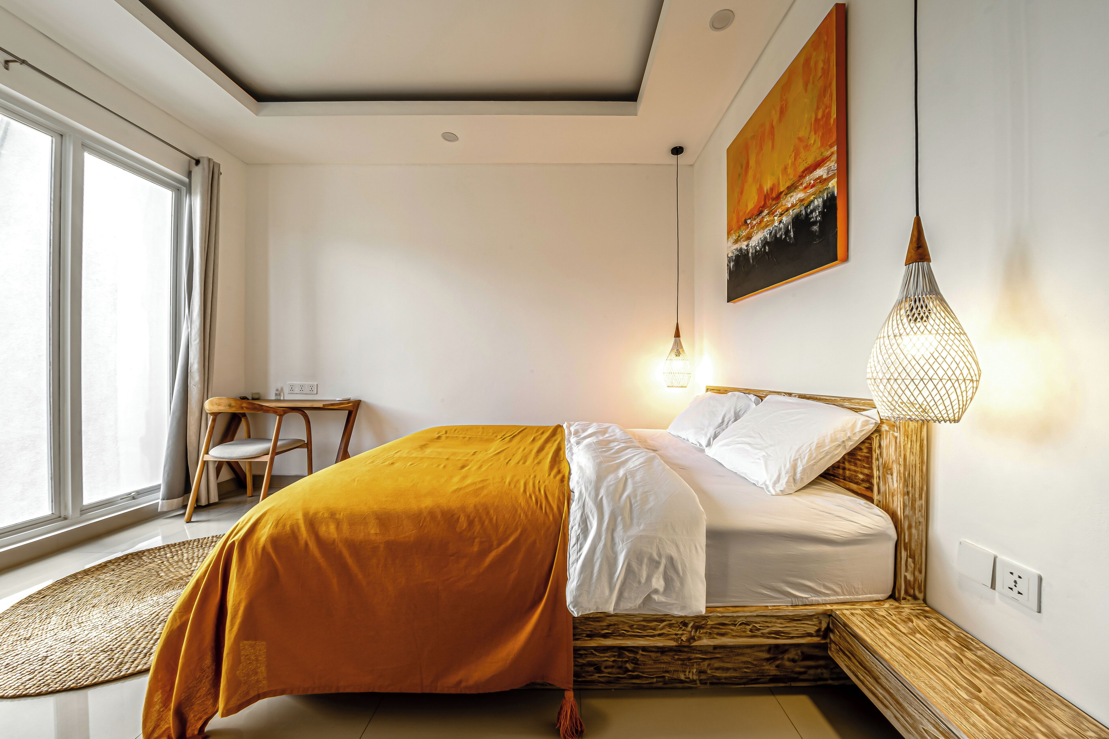 A modern bedroom with a bed, a desk, and a large window.