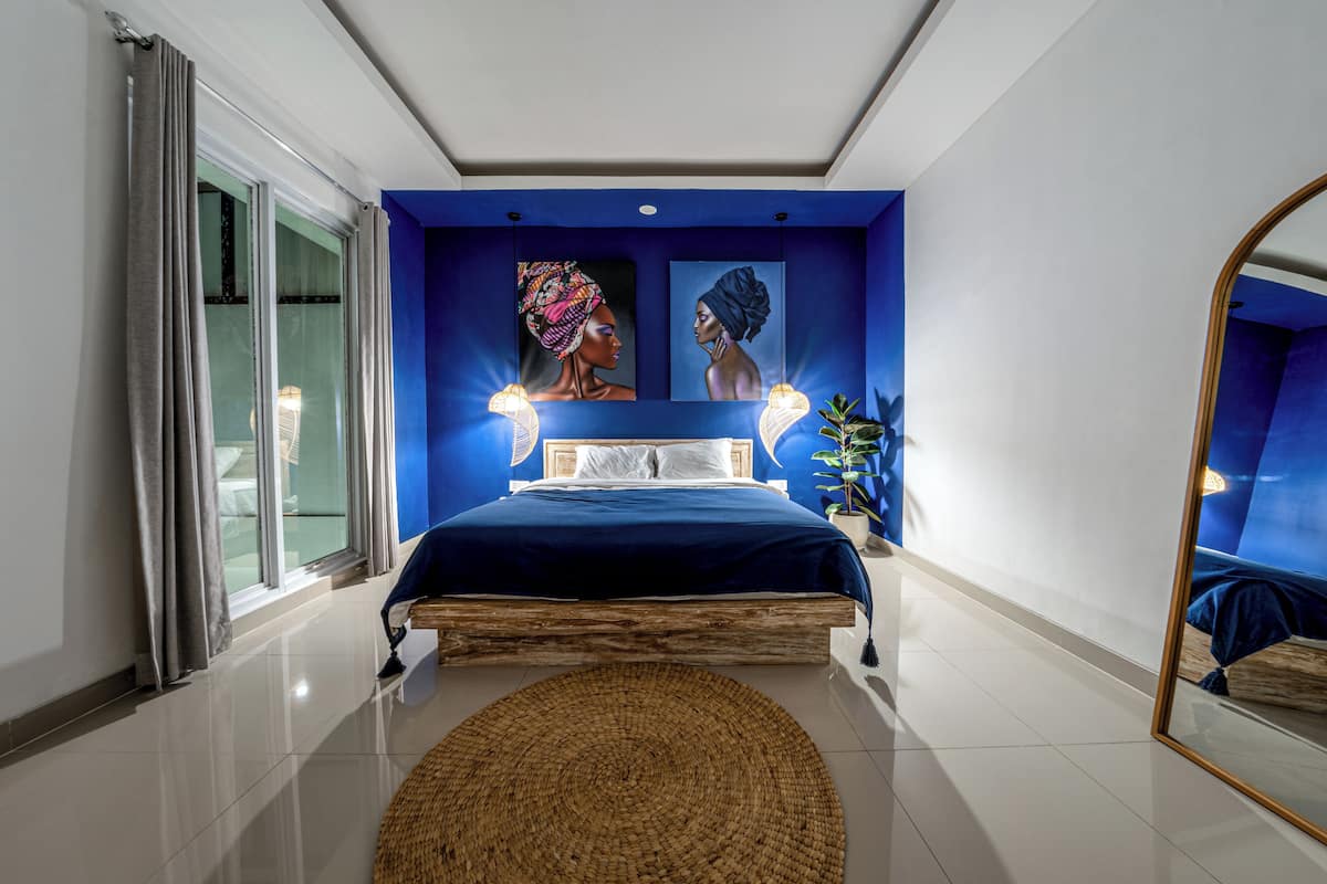Un dormitorio con cama, un espejo grande y obras de arte en la pared.