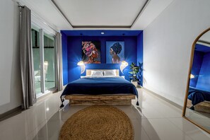 Un dormitorio con cama, un espejo grande y obras de arte en la pared.