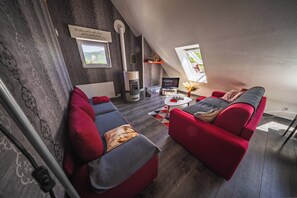Een knus loft-woonkamer met een open haard, rode banken en een televisie.