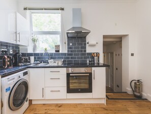 Eine moderne Küche mit Waschmaschine, großem Fenster und Blick ins Freie.