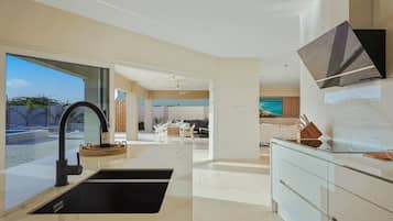 Une cuisine moderne avec un évier noir, des armoires blanches et un coin repas comprenant une table et des chaises blanches.