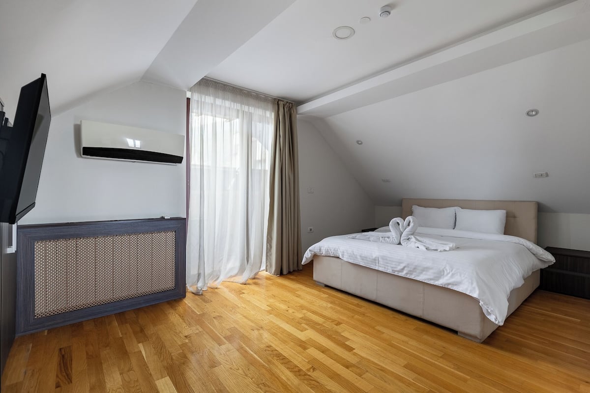 A bedroom with a bed, a TV, and a ceiling fan.