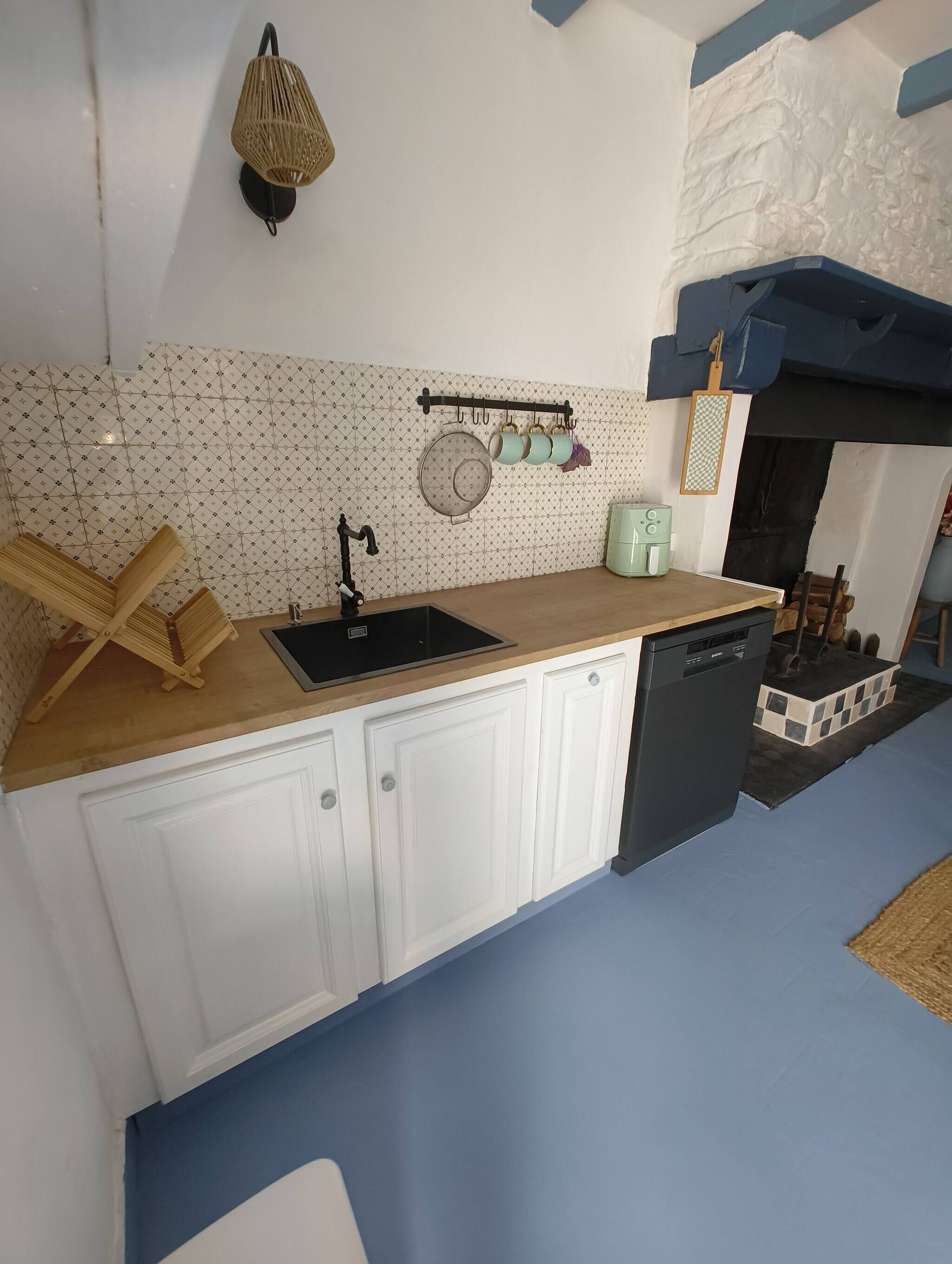 A kitchen with a sink, cabinets, a dish rack, and a stove.