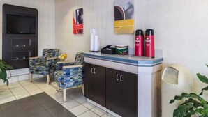 A reception area with a counter, chairs, a television, and a wall-mounted dispenser. - 2 Full Beds | Non-Smoking (Milan)
