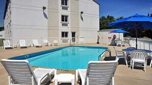 A swimming pool with lounge chairs and umbrellas, a building with multiple windows, and a fenced area. - 2 Full Beds | Non-Smoking (Milan)