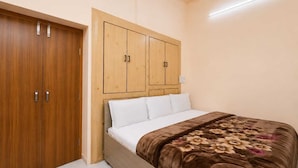 A bedroom with a bed, wooden wardrobe, and a ceiling fan. - Hotel Jannat Palace Near Jama Masjid (New Delhi)