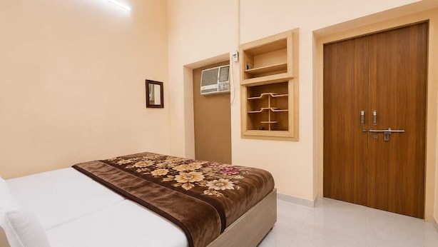 A bedroom with a bed, a wardrobe, a shelf unit, and an air conditioning unit. - Hotel Jannat Palace Near Jama Masjid (New Delhi)