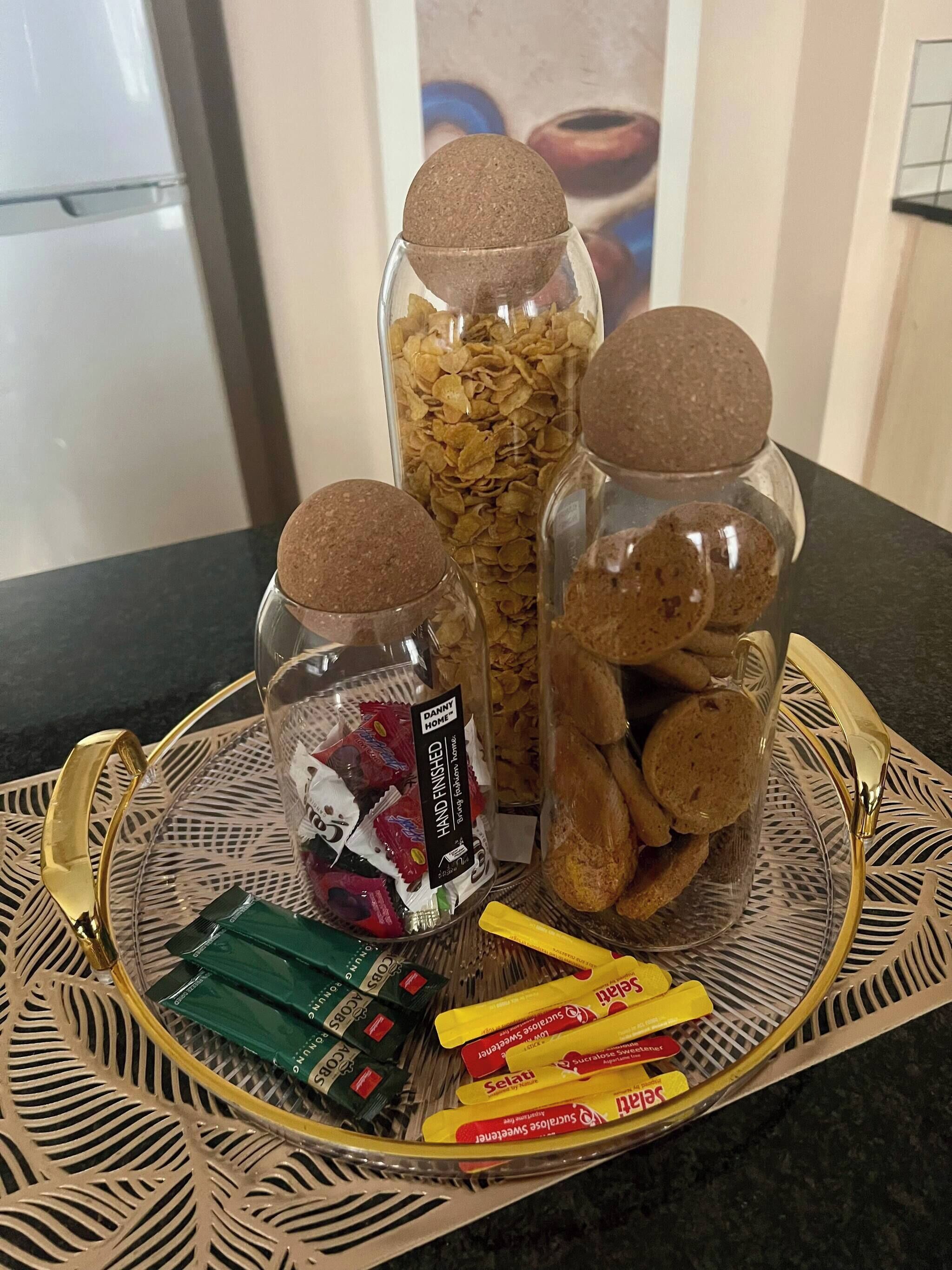 A tray with jars of snacks, a container of cookies, and packets of sweets.