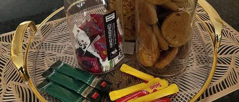 A tray with jars of snacks, a container of cookies, and packets of sweets.