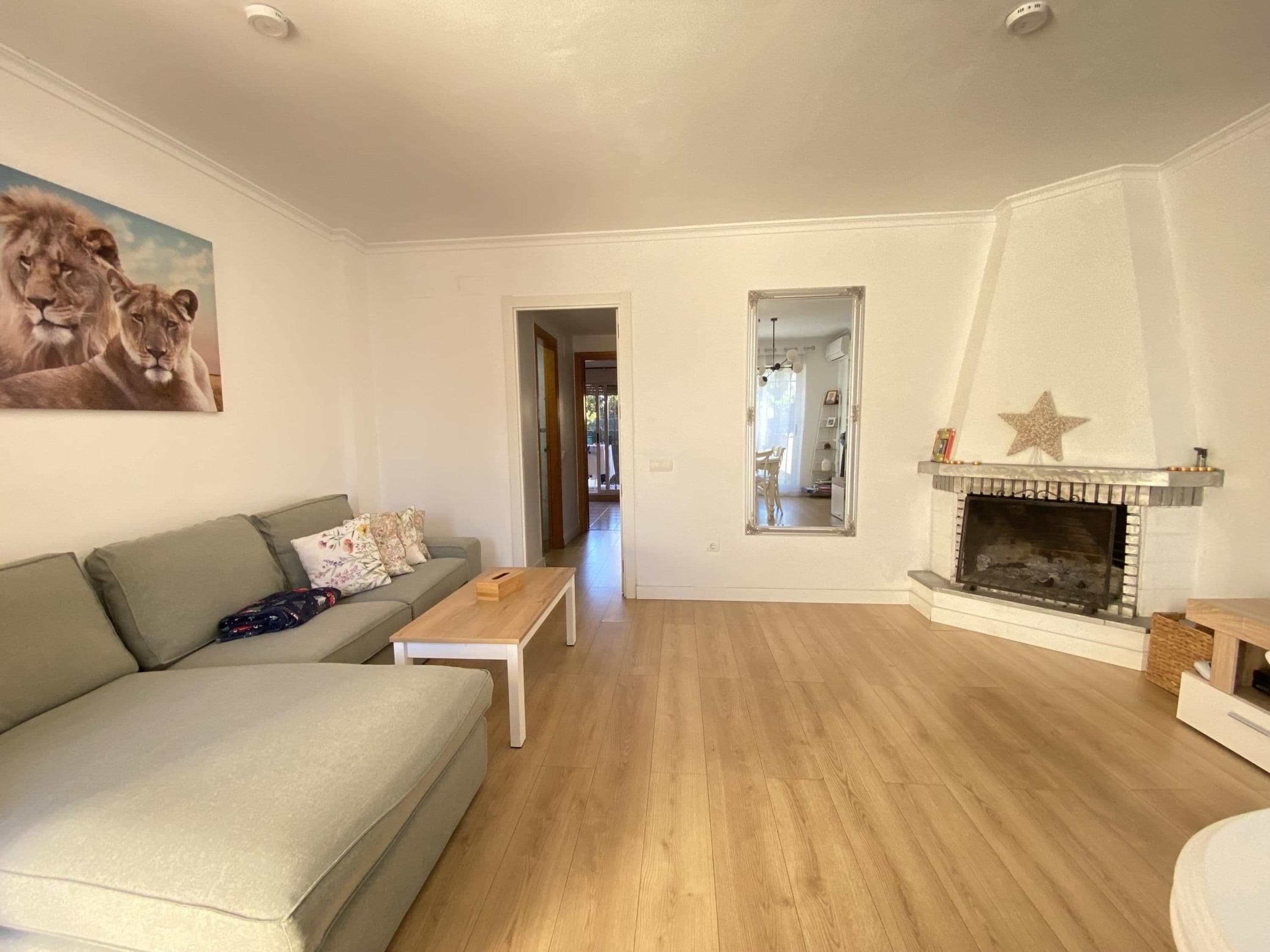 Ein Wohnzimmer mit einer Couch, einem Couchtisch, einem Kamin und einem Gemälde mit Löwen.