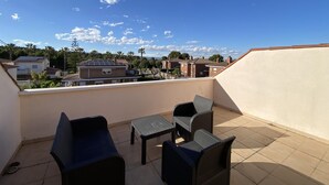 A rooftop terrace with outdoor furniture, a view of neighboring buildings, and a clear sky. - Th46 Casa Adosada en Salou Para 6 Personas (Salou)