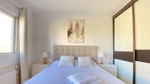 A neatly made bed with pillows, a bedside lamp, and a painting on the wall. - Th46 Casa Adosada en Salou Para 6 Personas (Salou)