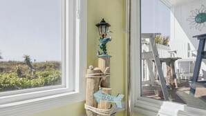A wooden post with a lantern and a 'BEACH' sign, a white chair, and a white fence outside a window. - Oceanfront 3BD/2BA-First Floor-Beautifully Decorated-Family Friendly (North Myrtle Beach)