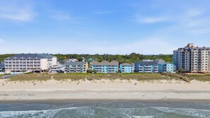 Ein Hotel direkt am Strand mit mehreren Gebäuden, einem Sandstrand und Meereswellen.