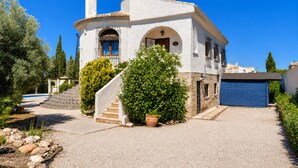 A white building with a blue garage door, a stone staircase, and a pool in the background. - Private Pool Villa La Siesta (El Chaparral)
