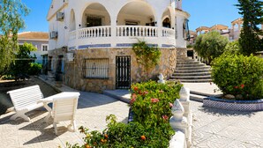 A two-story building with a white facade, stone accents, and a balcony with a railing. - Private Pool Villa La Siesta (El Chaparral)