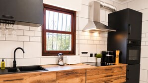 A modern kitchen with a black refrigerator, wooden cabinetry, a window with bars, and a stainless steel range hood. - Private Pool Villa La Siesta (El Chaparral)