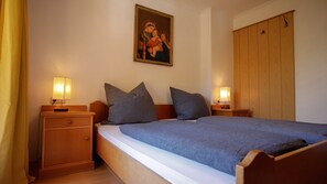 Ein Schlafzimmer mit einem Bett, zwei Nachttischen, einem Holzschrank und einem Wandbild.
