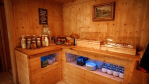 Ein Holzhäuschen im Inneren, mit einem Frühstücksbuffet, darunter Gläser, Teller und einer Glasvitrine.