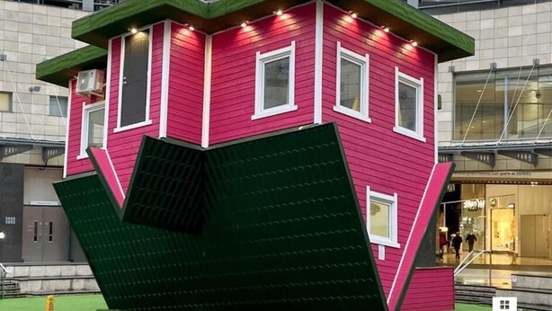 Een rood gebouw met een groen dak en veel ramen.