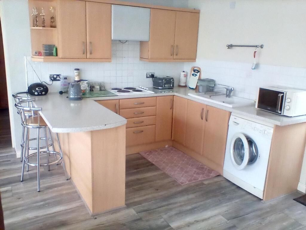 Una cocina compacta con una isla central, lavadora y microondas.