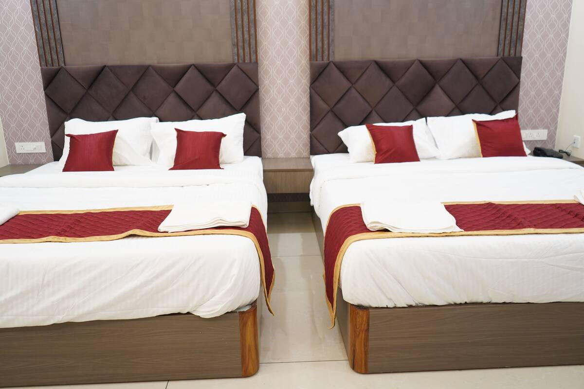 Dos camas gemelas idénticas con cabecera tapizada, ropa de cama blanca y detalles en rojo.