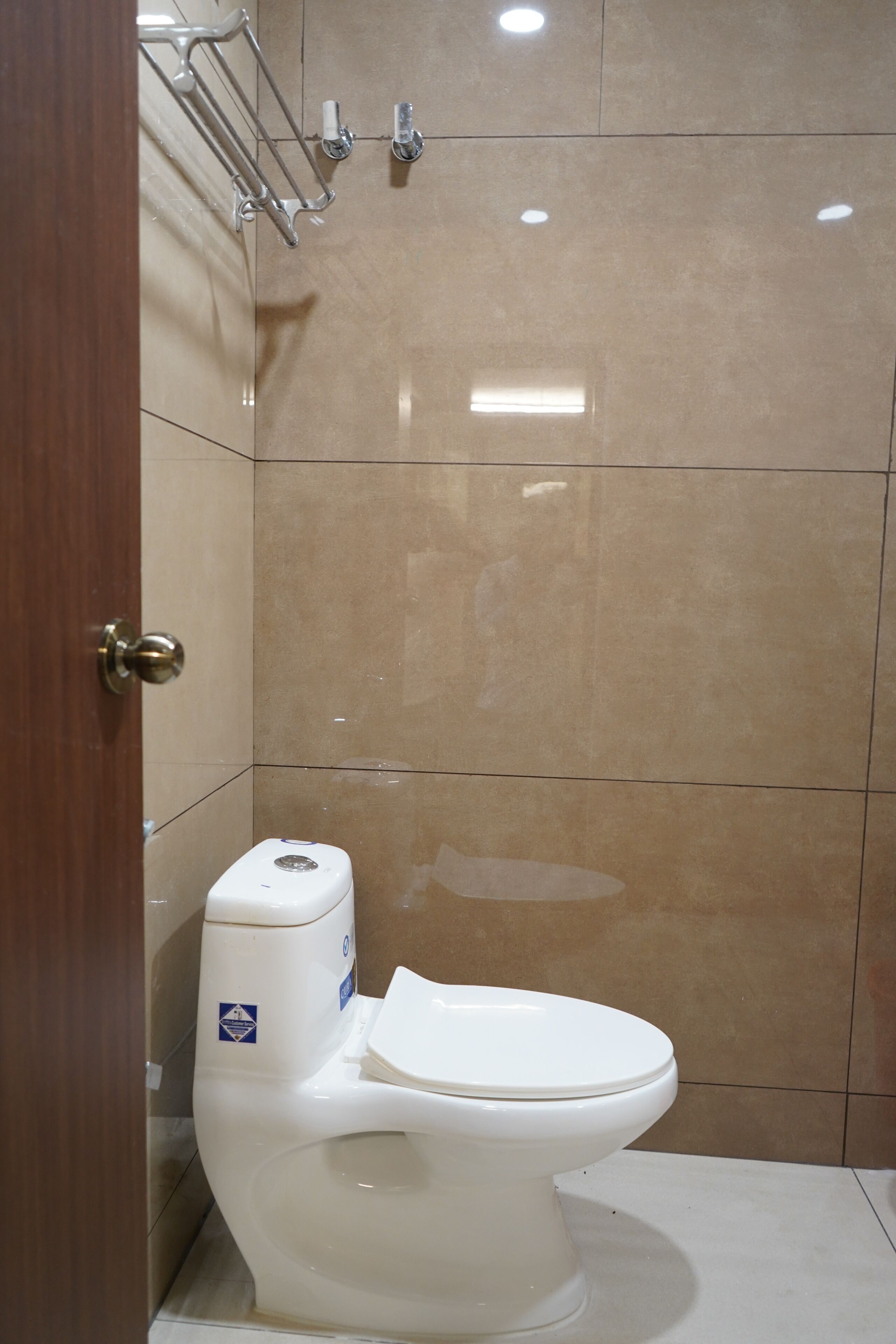 Casa de banho com sanita branca, zona de duche e parede revestida a azulejos.
