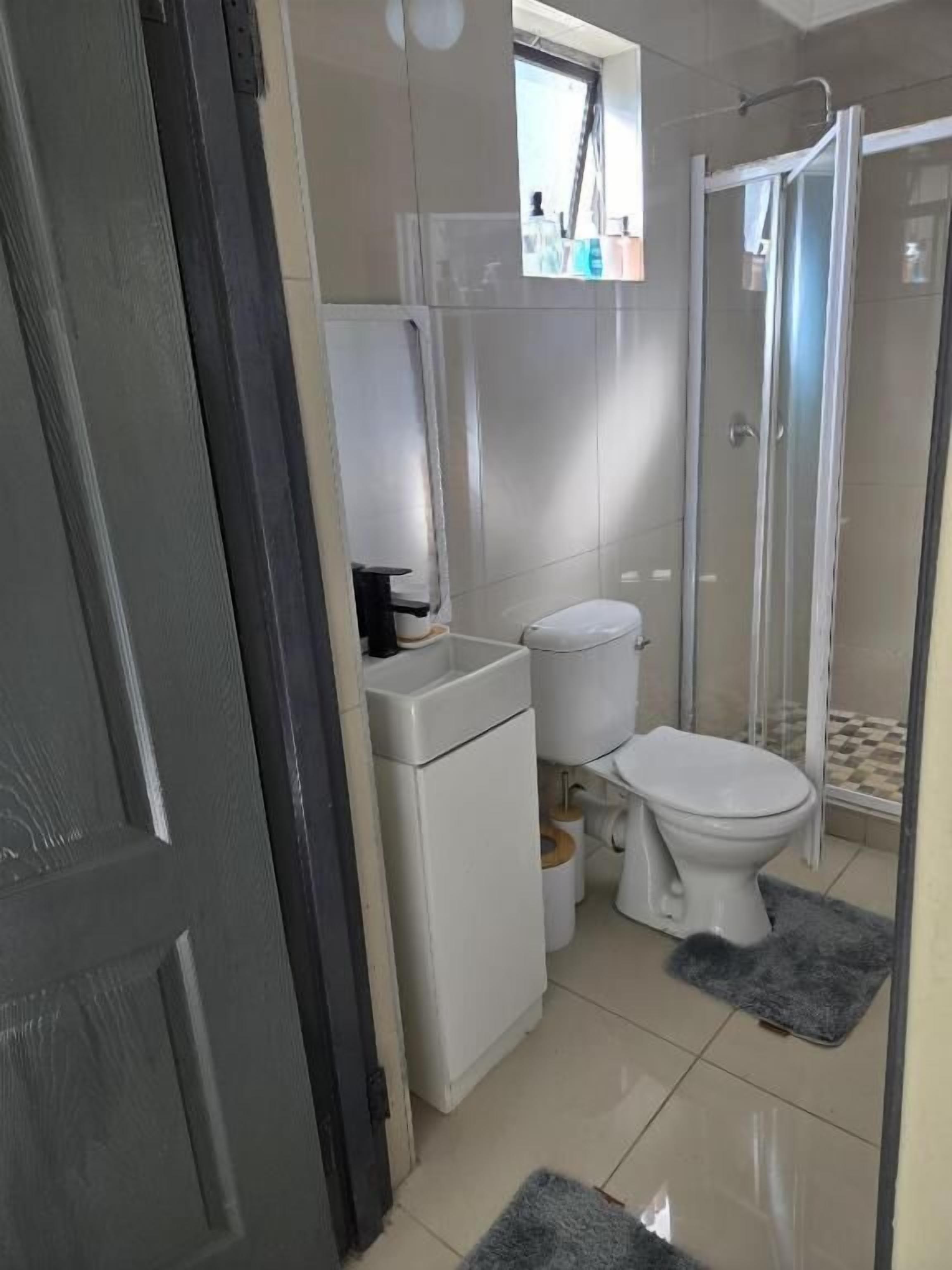 Ein Badezimmer mit Toilette, Waschbecken, Spiegel und Duschbereich.