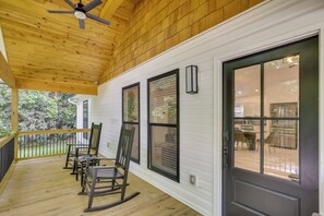 Eine überdachte Veranda mit Holzboden, Deckenventilator und einer Tür mit Glasfeldern.