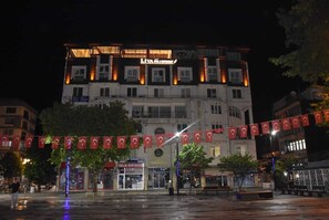A multi-story hotel with a prominent sign for 'LIVA' and 'DELTA' on the facade. There are flags hanging across the street, and a few trees are visible in front of the building. - Görele Liva Hotel (Görele)