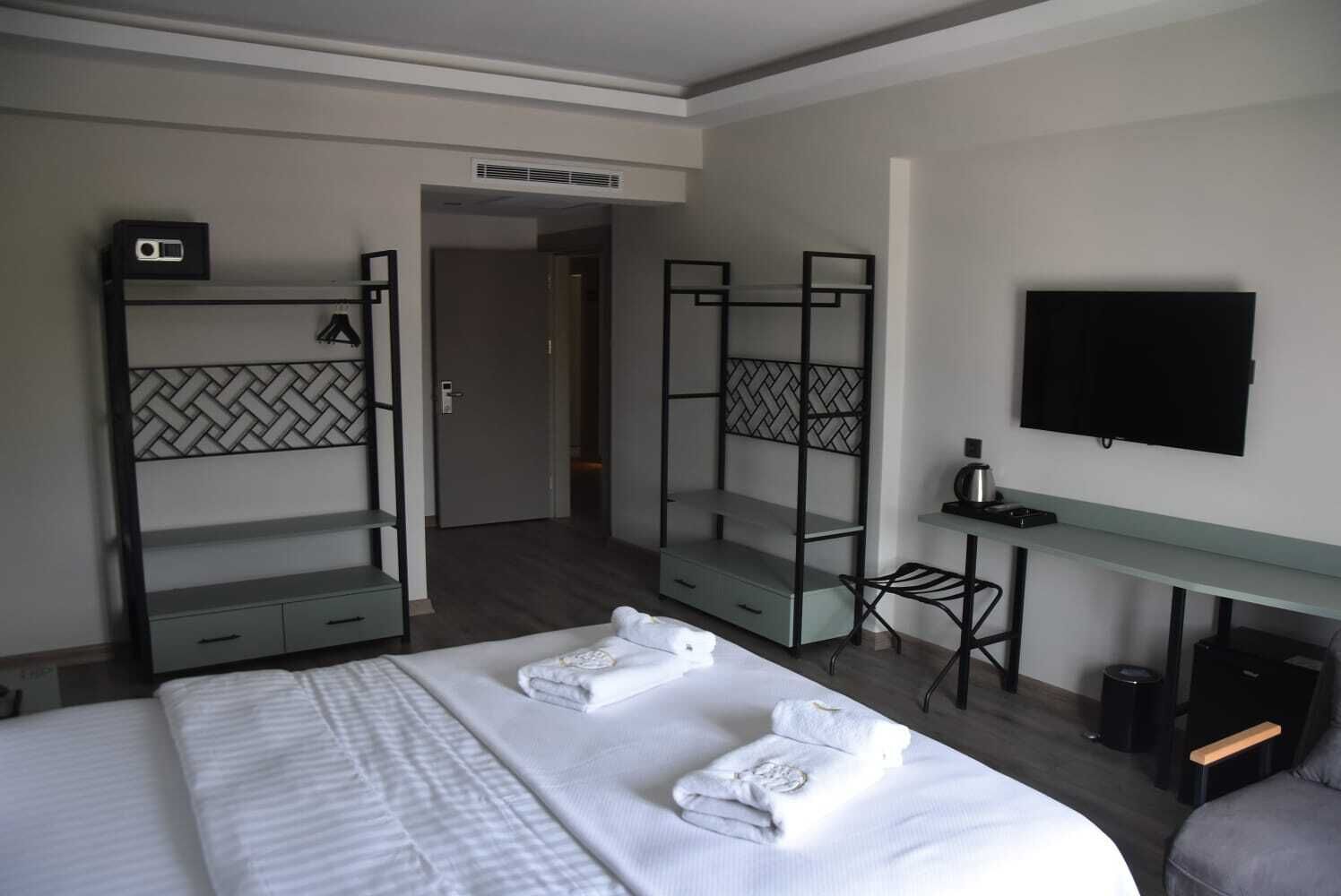 Habitación de hotel con una cama, dos literas, un escritorio, una silla, un televisor y una mesita.