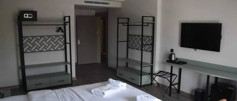Habitación de hotel con una cama, dos literas, un escritorio, una silla, un televisor y una mesita.