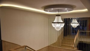 Un interior moderno con una escalera de madera, una lámpara de techo curva y una gran araña.
