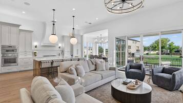 A spacious living room with a large sofa, a coffee table, and a dining area with a kitchen in the background.