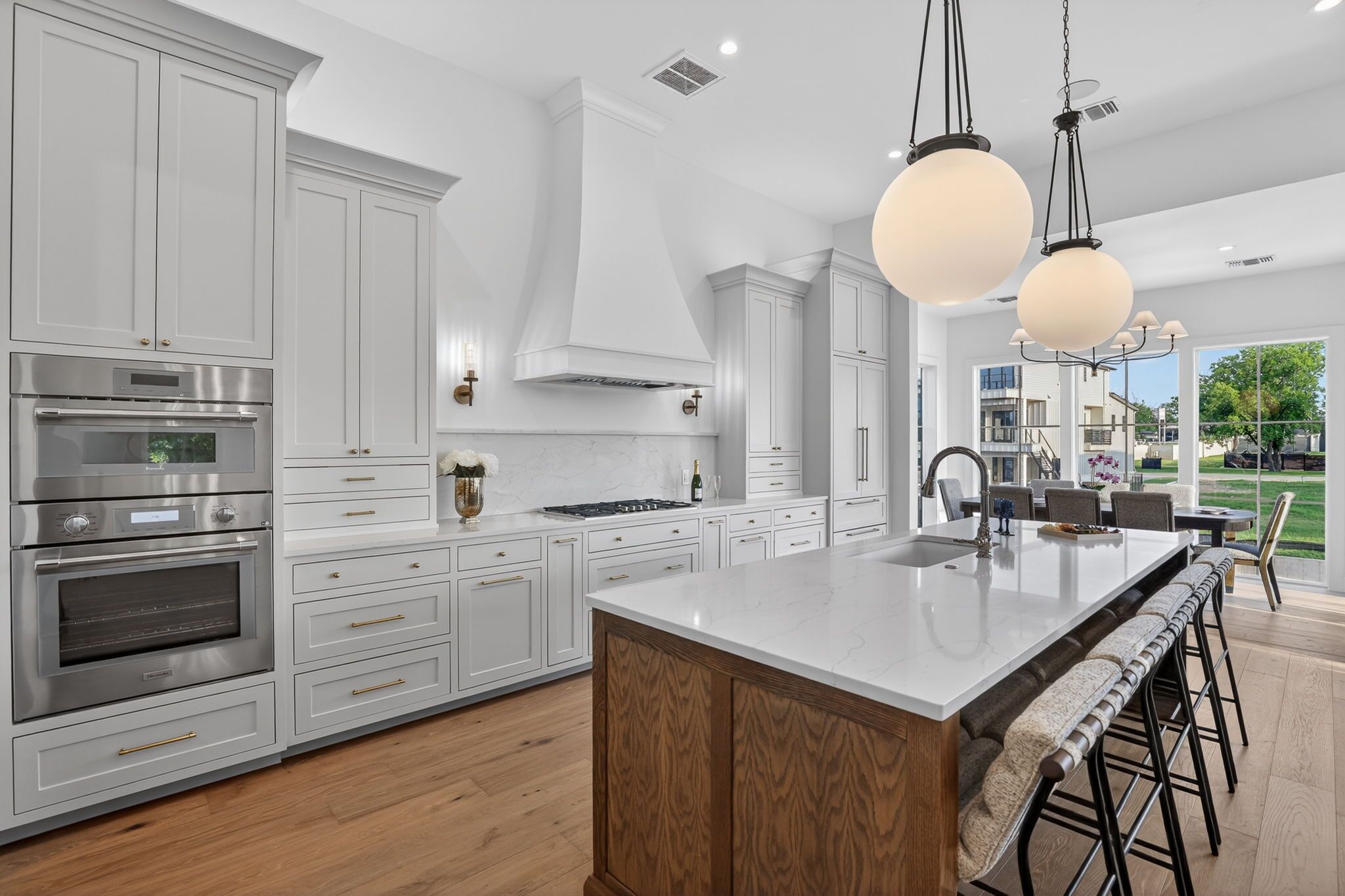 A modern kitchen with white cabinetry, stainless steel appliances, and a large island with bar stools.