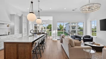 A modern kitchen with a central island, bar stools, and pendant lighting.