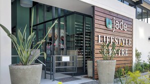 Een moderne entree van een gebouw, met een bord waarop 'the jade LIFESTYLE CENTRE' staat.