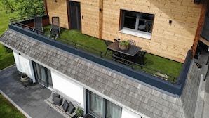 A modern house with a wooden exterior, a balcony with seating, and a small garden area. - Apartment Sonnseite for max. 5 persons with sun terrace (Teisendorf)