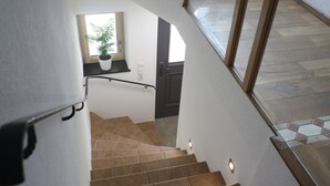 A staircase with a handrail, a potted plant, and a door at the bottom. - Apartment Sonnseite for max. 5 persons with sun terrace (Teisendorf)