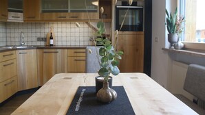 A kitchen with wooden cabinets, a black countertop, and a vase with green plants. - Apartment Sonnseite for max. 5 persons with sun terrace (Teisendorf)