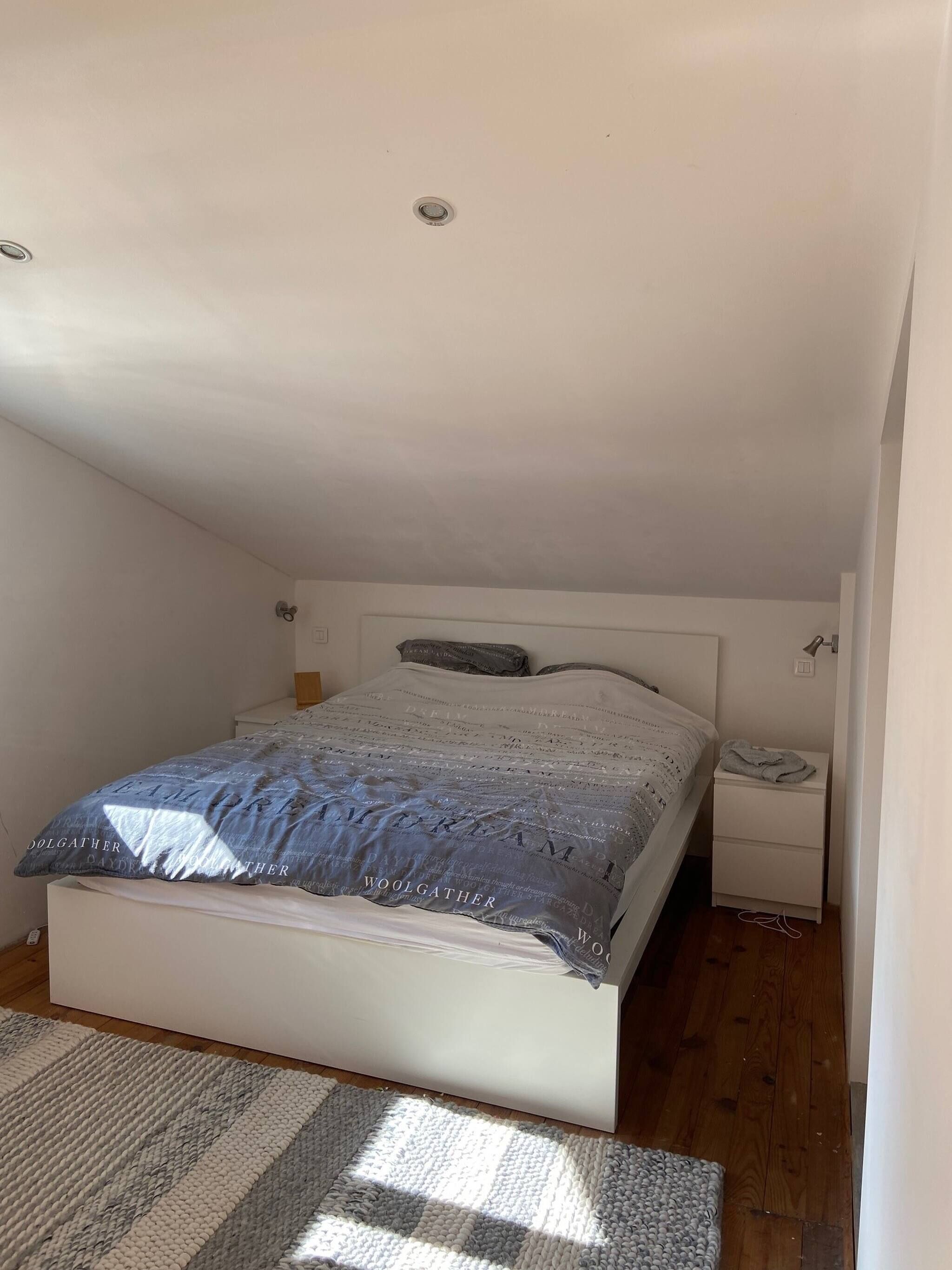 A bedroom with a bed, bedside table, and a nightstand.
