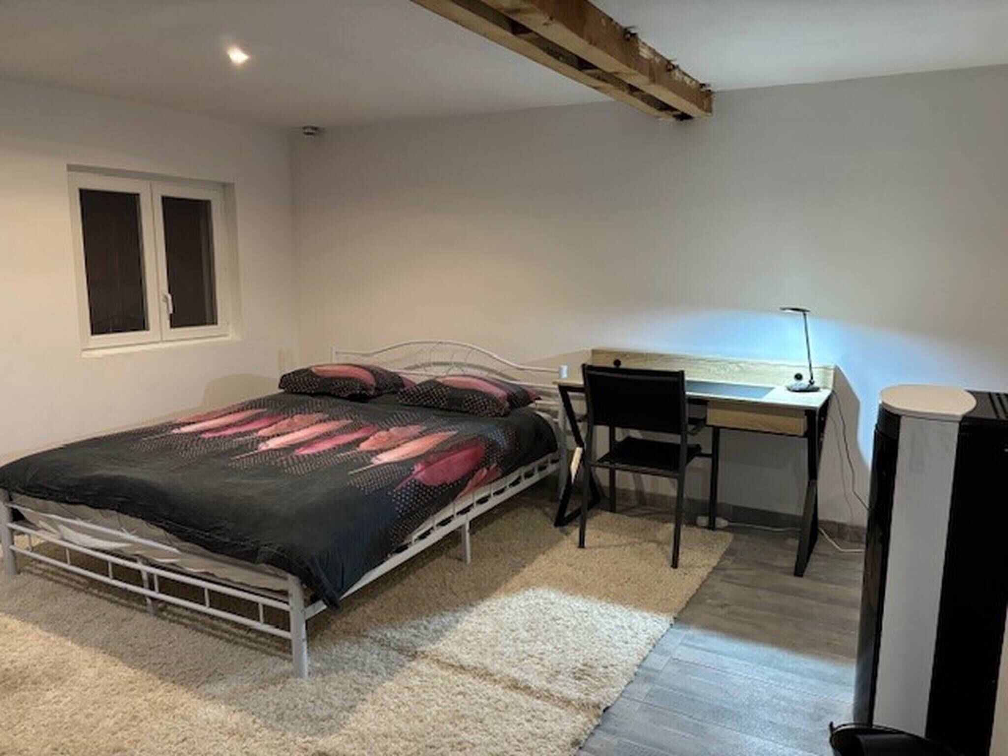 Une chambre à coucher avec un lit, un bureau, une chaise et un radiateur.